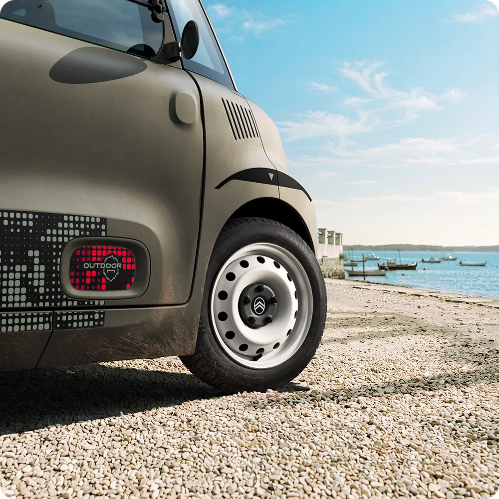 Primo piano della ruota della Citroën Ami Outdoor con cerchi in acciaio bianchi, una microcar elettrica compatta per la mobilità quotidiana